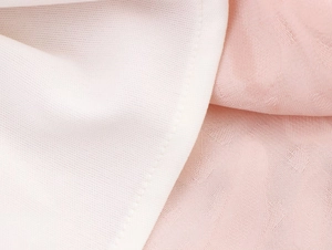 Vue macro du tissu jacquard rose et de la doublure en maille blanc cassé de la robe