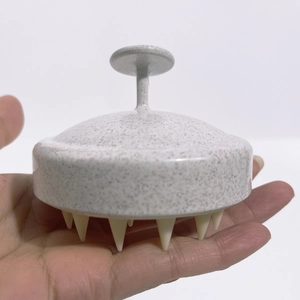Detail showing wheat straw head massage brush with ergonomic handle and soft white bristles