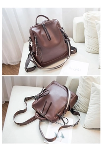 Detail view of brown soft leather backpack on a white sofa with adjustable straps