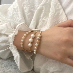 Close-up of three 18K gold plated bracelets featuring natural freshwater pearls