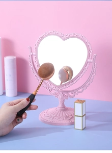 Detailed view of pink heart-shaped vanity mirror with vintage floral carved base