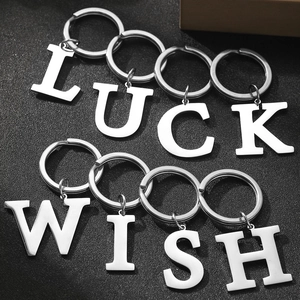 Polished silver metal letter keychains spelling LUCK and WISH on a black texture