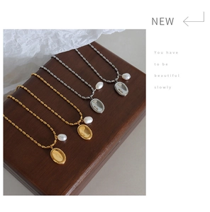 Detailed shot of titanium steel pearl necklaces with oval pendants in gold and silver