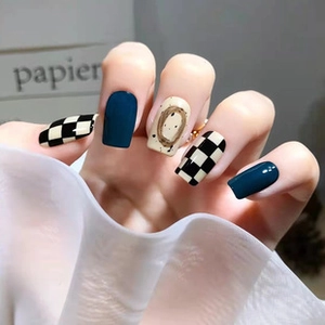 Detail of long ballerina nails featuring navy blue, checkered, and beige circular patterns