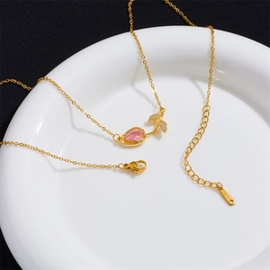 Elegant gold tulip necklace with pink gemstone pendant and zircon leaves on white ceramic tray