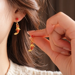 Détail des boucles d'oreilles carpe koï sur un mannequin avec émail rouge et doré