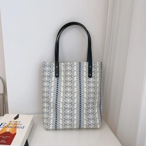 Detail of floral tote bag with blue stripes, leather handles and gold rivet accents