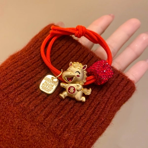 Détail d'un élastique à cheveux rouge avec pendentif cheval doré et cœur brillant