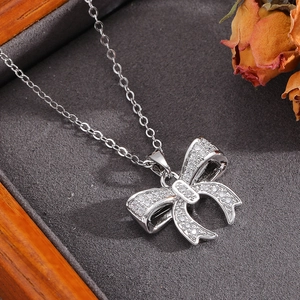 Close-up of silver bow pendant necklace with shimmering zircon stones and pearl detail
