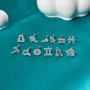 Twelve zodiac sign cartilage stud earrings set with sparkling cubic zirconia on green silk