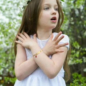 Detailed view of kids gold bracelet with engravable bar and red gemstone on wrist