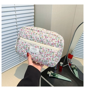 Detailed shot of quilted floral cosmetic bag with zipper being held in a vanity setting