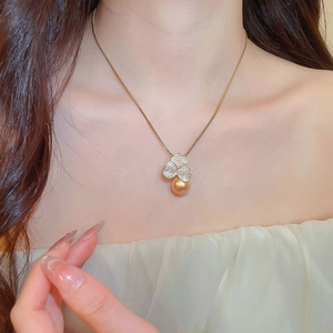 Close-up of gold plated necklace featuring a zircon flower pendant and a lustrous pearl