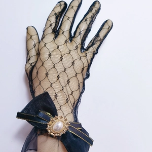 Detail of black lace Lolita glove featuring a bow with pearl and rhinestone brooch