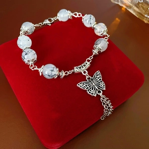 Gros plan d'un bracelet en perles de verre avec papillon et glands sur un écrin
