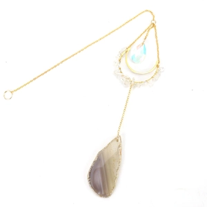 Detail of agate slice moon sun catcher with golden chains and colorful crystal pendant