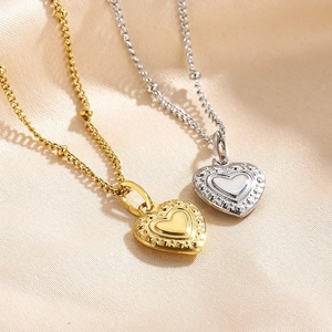 Minimalist gold and silver heart pendants on beaded titanium steel chains over silk fabric