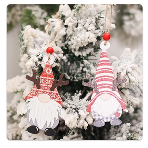 Detailed view of wooden gnome ornaments with reindeer antlers hanging on a snowy Christmas tree