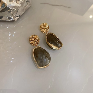 Detail of vintage geometric earrings with gold hammered metal and grey resin pendants