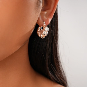 Close-up of a silver irregular shell-shaped earring with a metallic twisted texture