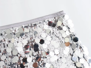 Macro shot of silver sequins stitched on white mesh fabric with grey bound edges