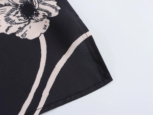 Close-up of black fabric with beige floral print and detailed stitching on the sleeve edge