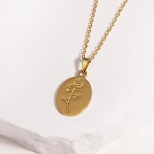Detailed close-up of golden oval pendant featuring embossed rose on white stone base