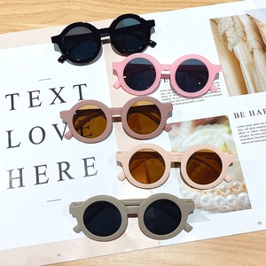 Five pairs of kids round matte sunglasses in assorted colors on a fashion magazine