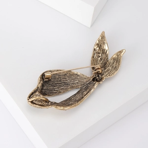 Detail view of antique bronze alloy ribbon brooch with textured surface and pin clasp