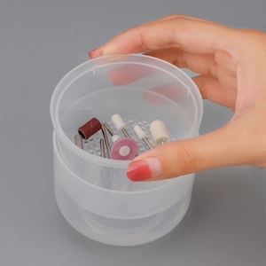 Manicure nail drill bit set in a plastic storage box held by hand for nail tool cleaning
