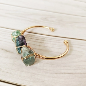 Detailed macro view of handmade copper wire wrap with natural green and purple fluorite stones