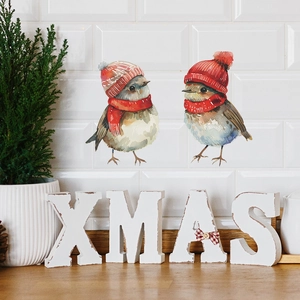 Christmas window decals with two watercolor birds in red hats on a white subway tile wall