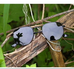 Outdoor shot of irregular metal sunglasses with black polarized lenses on a wooden branch