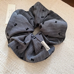 Détail d'un chouchou gris rayé avec flocage nœud et étiquette tissée Happiness