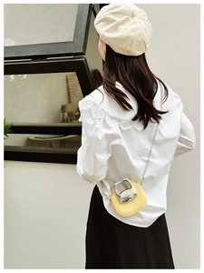 Detail view of mini yellow chain bag with creative metal ring-pull buckle on a model