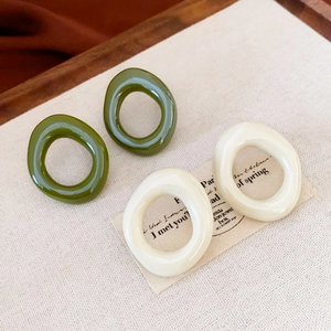 Irregular resin hoop earrings in olive green and cream on a canvas background