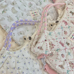 Detail of quilted floral canvas bag with cute cartoon prints and rope handles