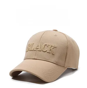 Detailed view of beige baseball cap with 3D gold 'BLACK' embroidery and textured fabric