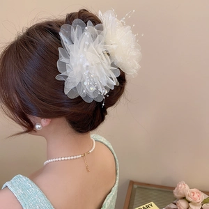 Detail of elegant white mesh flower hair claw with delicate bead accents on a model