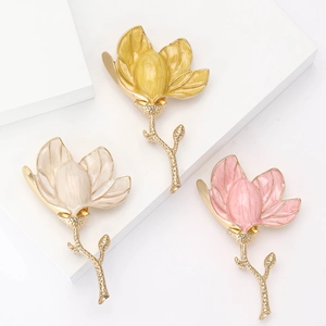 Detailed close-up of colorful enamel magnolia brooches in yellow, beige and pink