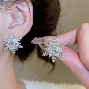 Close-up of sparkling snowflake earrings with brilliant zircons on a silver needle base