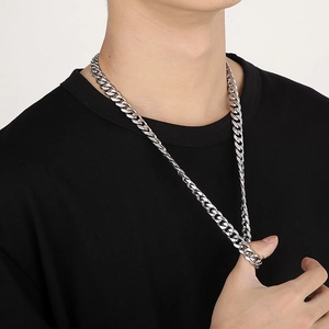 Close-up of a silver Cuban link chain necklace worn on a black shirt for a street look