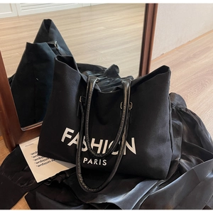 Detail der schwarzen Canvas-Tragetasche mit Fashion Paris-Druck und Ledergriffen
