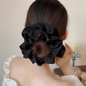 Elegant large black satin scrunchie for women shown on a model hair for styling