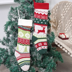 Knitted Christmas stockings with reindeer and tree patterns hanging on a decorated tree