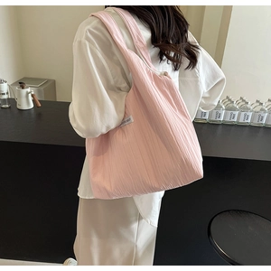 Detailansicht der rosa plissierten Umhängetasche mit Etikett, von Model getragen