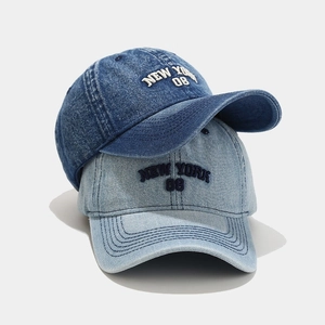 Detail of washed denim baseball caps in dark and light blue with NEW YORK 08 embroidery