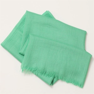 Detail view of mint green cotton linen scarf showing soft fabric texture and fringe edges