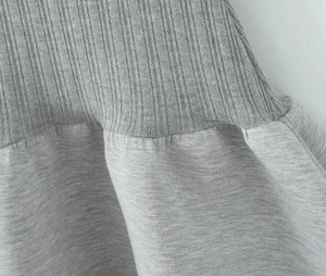 Détail d'une robe polo grise montrant des coutures en maille côtelée et jersey texturé