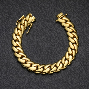 Detailed view of a gold-plated Cuban link bracelet on a textured black leather surface